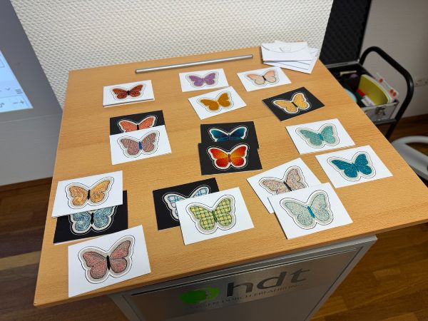 Tisch mit vielen bunten Schmetterlingsbildern.