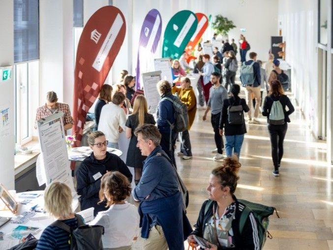 Mit mehreren Personen gefüllter Wandelgang an Treffpunkten mit bunten Beachflags. Mit mehreren Personen gefüllter Wandelgang an Treffpunkten mit bunten Beachflags.