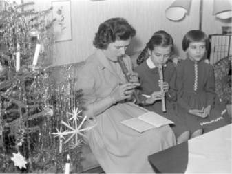 Eine Frau sitzt mit zwei Mädchen auf dem Sofa und spielt Blockflöte. Eine Frau sitzt mit zwei Mädchen auf dem Sofa und spielt Blockflöte.