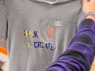 Lehrkraft hält selbst gestaltetes T-Shirt in den Händen. Lehrkraft hält selbst gestaltetes T-Shirt in den Händen.